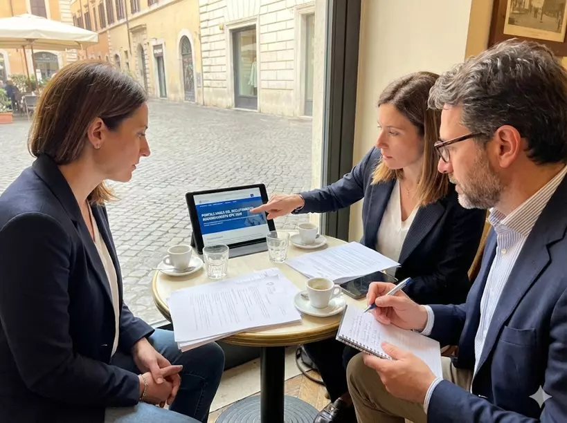 Aggiornamento Punteggio GPS 2026-2028: alcuni docenti si confrontano sul punteggio GPS davanti ad un pc seduti al tavolino di un bar