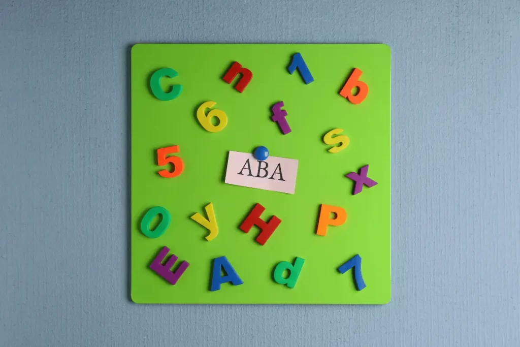 Foglio colorato con formine di lettere e numeri con al centro la scritta ABA