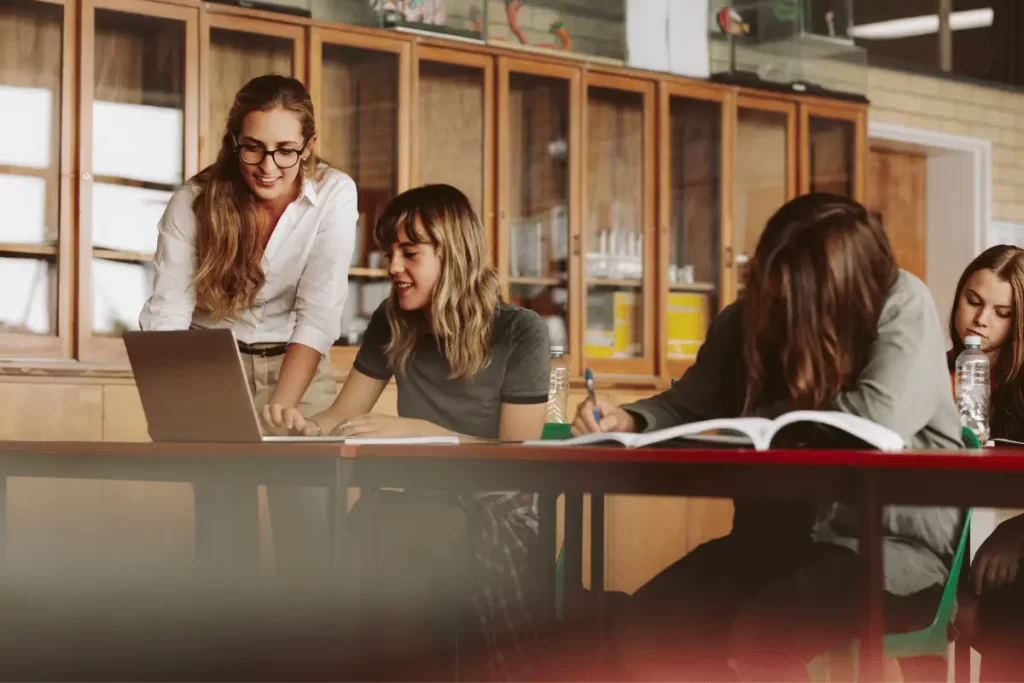 una docente tra i banchi degli alunni verifica gli esercizi