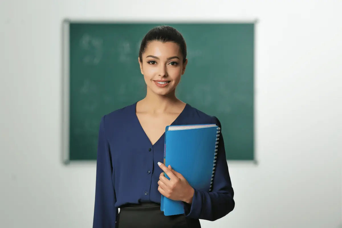 Professoressa con il mano il registro e la lavagna alle spalle