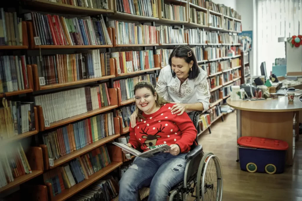 docente di sostegno in biblioteca con un'alunna in carrozzina