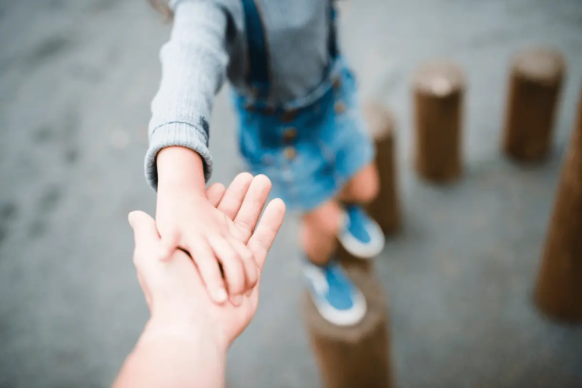 un bambino in equilibrio su un palo stringe la mano di un OPI